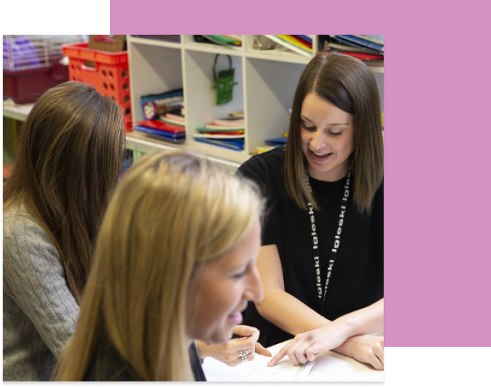 People interacting at a desk in a classroom environment.