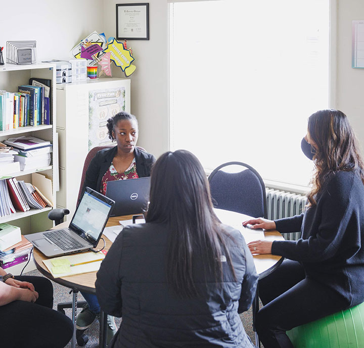 Women sitting around table with laptops.