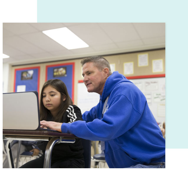 Teacher helping student at laptop.