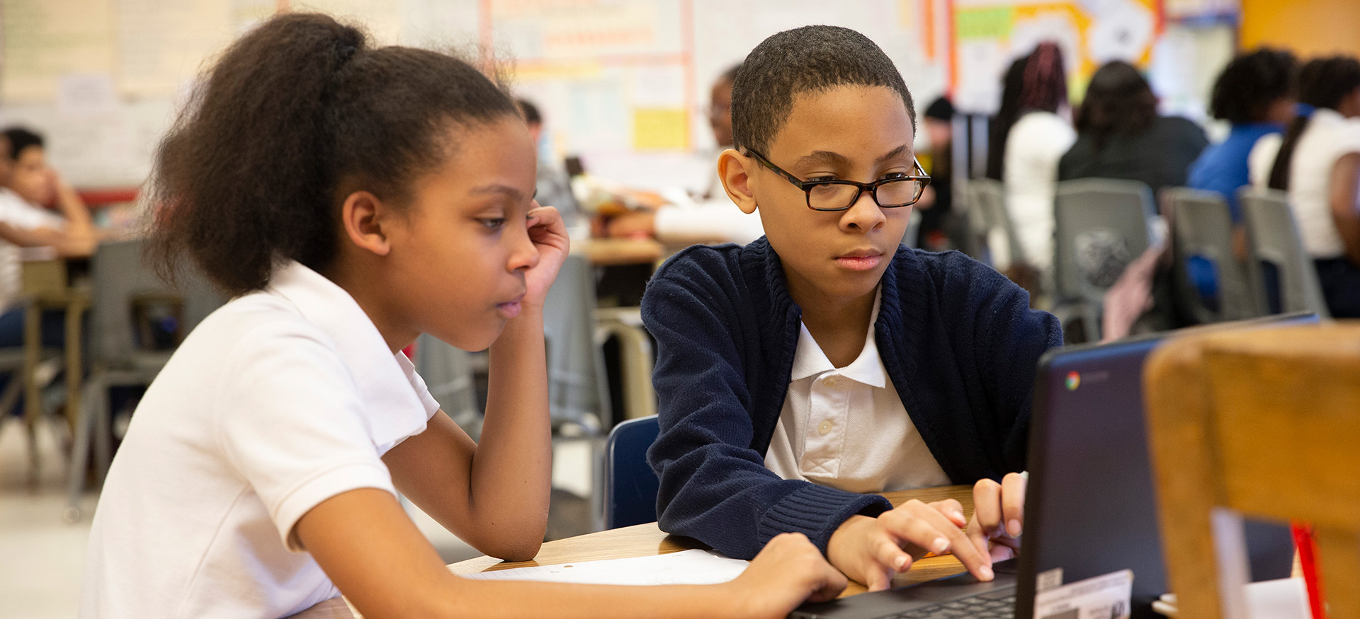 两个学生在教室里用笔记本电脑一起工作。